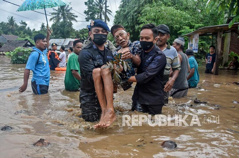 Sejumlah anggota Brimob Polda NTB mengevakuasi warga dari lokasi banjir di Dusun Kebon Lauk, Desa Sesela, Kecamatan Gunungsari, Lombok Barat, NTB, Senin (6/12/2021). Banjir yang terjadi karena hujan lebat dan luapan air Sungai Meninting di wilayah Gunungsari tersebut mengakibatkan ratusan rumah warga terendam.