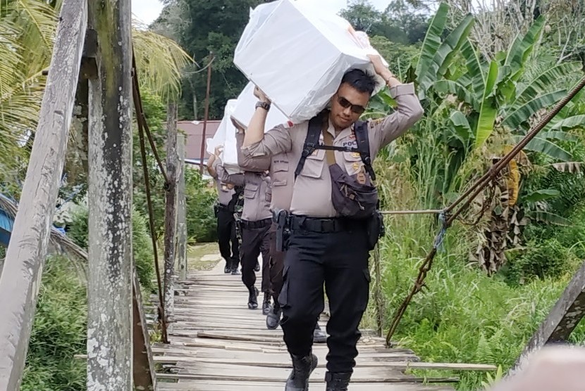 Sejumlah anggota kepolisian memanggul logistik Pemilu serentak 2019 melintasi hutan menuju Dusun Buntan di Desa Bungkang, Kecamatan Sekayam, Kabupaten Sanggau, Kalimantan Barat, Selasa (16/4/2019).