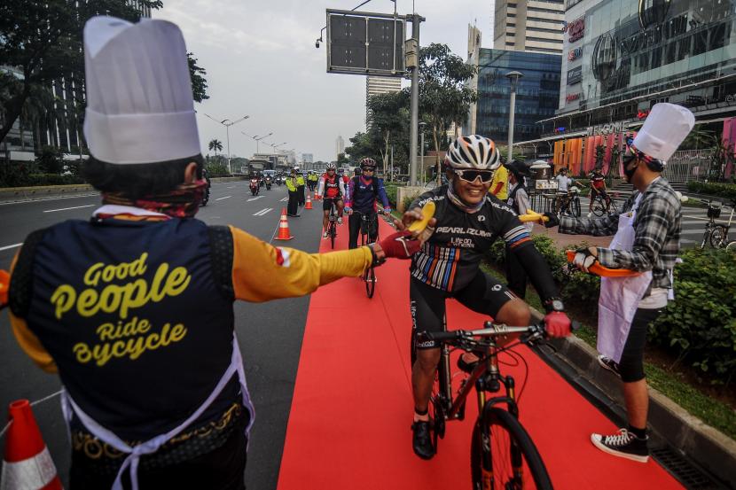 Sejumlah anggota Komunitas Bike To Work Indonesia membagikan makanan kepada pesepeda di kawasan Sudirman, Jakarta.