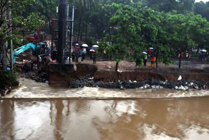   Sejumlah anggota Kopassus menambal tanggul jebol di aliran Banjir Kanal Barat, Menteng, Jakarta Pusat, Jumat (18/1).