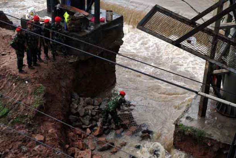 Sejumlah anggota Kopassus menambal tanggul jebol di aliran Banjir Kanal Barat, Menteng, Jakarta Pusat, Jumat (18/1).