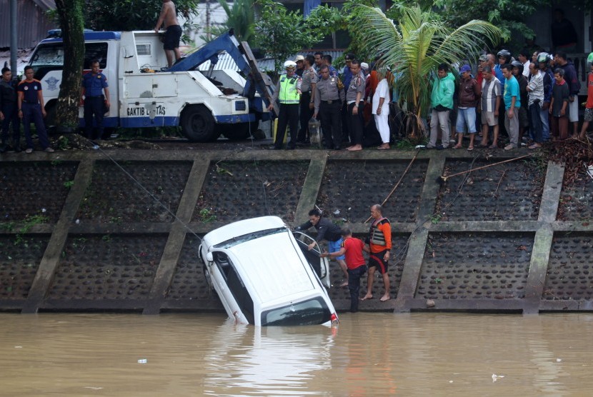 Sejumlah anggota Polisi, Badan Penanggulangan Bencana Daerah (BPBD) Kota Padang dan warga mengevakuasi mobil yang masuk dalam banjir kanal Bandar Bakali, Padang, Sumatera Barat, Senin (21/1/2019)