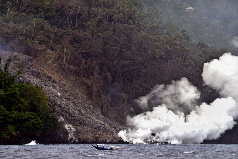 Sejumlah anggota polisi yang mengangkut bantuan logistik dengan perahu motor melintas di dekat lokasi guguran material vulkanik Gunung Karangetang di Pulau Siau, Kabupaten Kepulauan Sitaro, Sulawesi Utara, Kamis (7/2/2019).