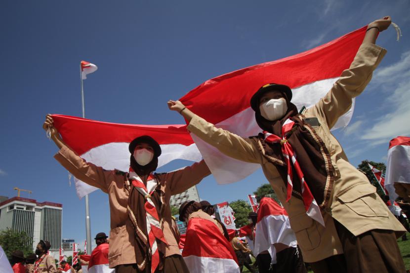 Sejumlah anggota Pramuka membentangkan Bendera Merah Putih pada acara Gerakan Nasonal Pembagian 10 Juta Bendera Merah Putih di Gedung Negara Grahadi, Surabaya, Jawa Timur, Ahad (14/8/2022). Kegiatan tersebut sebagai salah satu upaya dalam meningkatkan patriotisme dan nasionalisme masyarakat di seluruh Indonesia. 