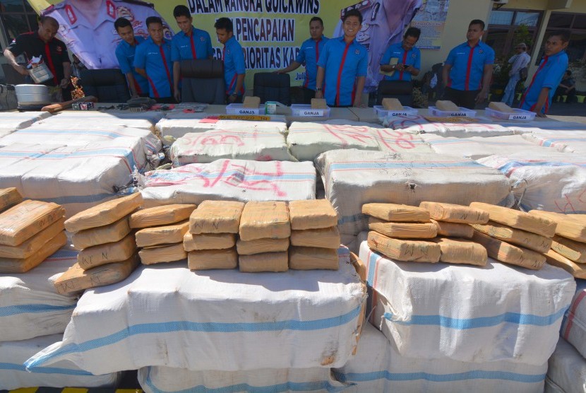 Sejumlah anggota Satnarkoba Polres Lampung Selatan berada disamping tumpukan ribuan paket daun ganja kering hasil tangkapan saat gelar perkara kasus kejahatan narkotika di Mapolres Lampung Selatan, Kamis (9/7). 
