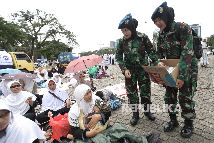 Sejumlah anggota TNI berjilbab membagikan air minum saat melakukan pengamanan dalam aksi Bela Islam III di kawasan silang Monas, Jakarta, Jumat (2/12).