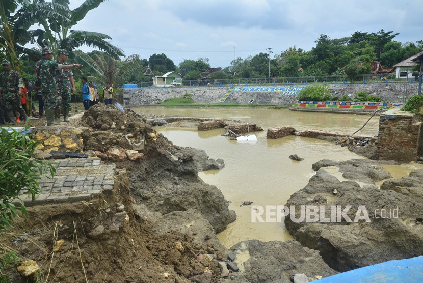 Sejumlah anggota TNI dan warga menyaksikan tanggul bendungan Gelapan yang jebol di Desa Gelapan, Gubug, Grobogan, Jawa Tengah, Kamis (9/1/2020). J