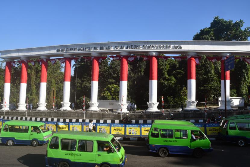 Sejumlah angkot melintas di depan Lawang Salapan yang dibalut bendera Merah Putih di jalan Otista, Kota Bogor, Jawa Barat, Senin (8/8/2022). 