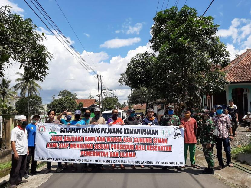 Sejumlah aparat dan warga Kampung Gunung Siman, Kelurahan Cigantang, Kecamatan Mangkubumi, Kota Tasikmalaya, menyambut salah seorang pasien Covid-19 yang pulang usai menjalani isolasi di rumah sakit, Sabtu (11/4). Sambutan itu dilakukan untuk memberi dukungan moril kepada pasien dan keluarganya. Pasien itu diperbolehkan pulang, tapi tetap harus menjalani isolasi mandiri di rumahnya.