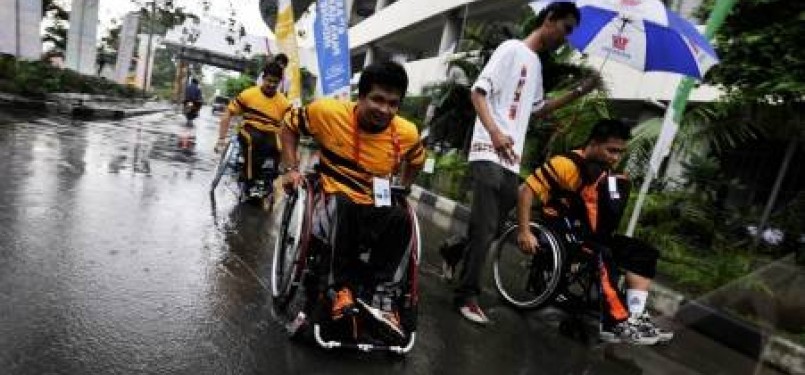 Sejumlah atlet disabilitas Malaysia berjalan menembus hujan yang mengguyur kawasan arena Atletik ASEAN Para Games (APG) VI saat tiba di Stadion Manahan, Solo, Jawa Tengah, Selasa (13/12). 