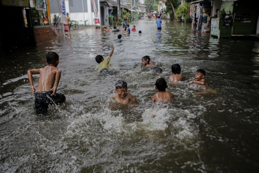Sejumlah bocah bermain di jalanan yang terendam banjir di Margasari, Karawaci, Kota Tangerang, Banten, Rabu (11/5/2022). Hujan deras yang mengguyur sejak Selasa (10/5) malam mengakibatkan kawasan tersebut terendam banjir hingga ketinggian 70 cm.