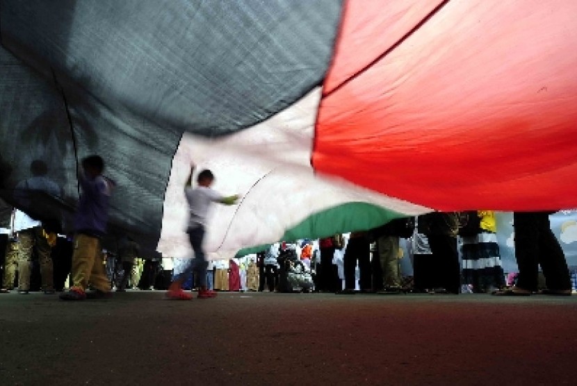 Sejumlah bocah bermain dibawah bendera Palestina saat aksi simpatik untuk Gaza di Bunderan HI,