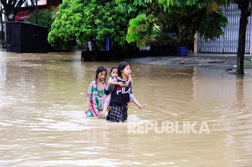Sejumlah bocah melintasi banjir di Pasir Pengaraian, Rokan Hulu, Riau, Kamis (24/12/2020). Banjir dari luapan Sungai Batang Lubuh disebabkan tingginya intensitas curah hujan dan derasnya kiriman air dari sekitar Bukit Barisan.