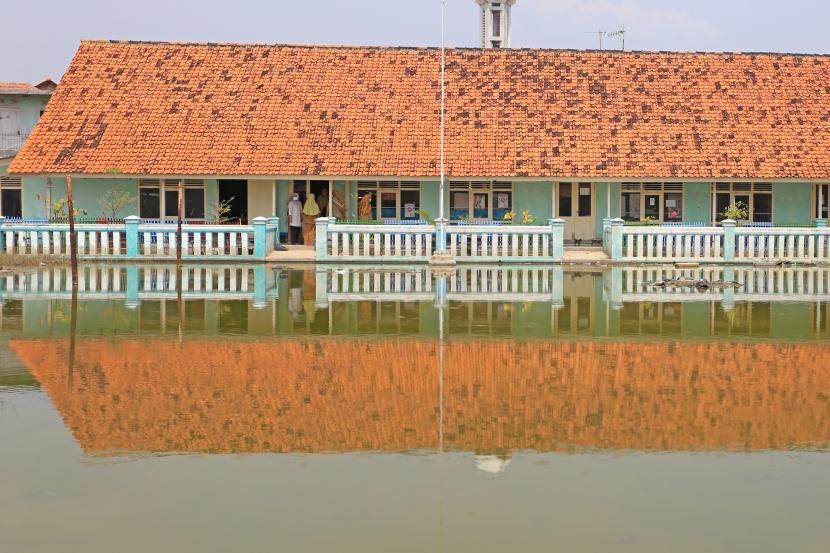 Sejumlah guru mengajar di SDN Eretan Wetan 1 yang terendam banjir rob di Desa Kandanghaur, Indramayu, Jawa Barat, Senin (23/8/2021). Banjir rob yang sering melanda daerah itu membuat aktivitas belajar di sekolah tersebut terganggu. 