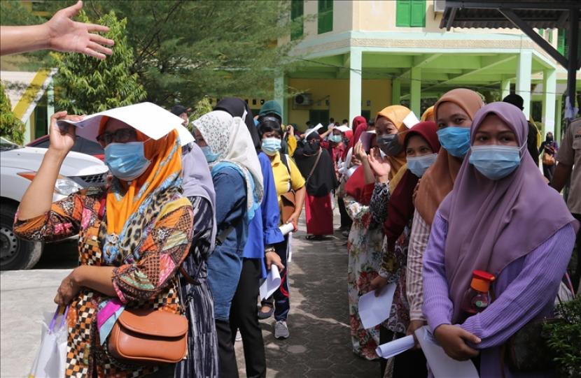 Sejumlah guru mengantre untuk mendapatkan vaksin virus korona di Medan, Indonesia pada 16 Juni 2021. Pemerintah Indonesia memulai vaksinasi untuk para guru menjelang pembelajaran tatap muka pada bulan Juli.