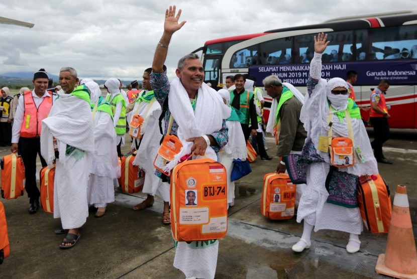 Sejumlah Jamaah calon haji kloter pertama Embarkasi Aceh melambaikan tangan sebelum naik ke pesawat udara di Bandara internasional Sultan Iskandar Muda, Aceh Besar, Aceh, Sabtu (20/7/2019). 