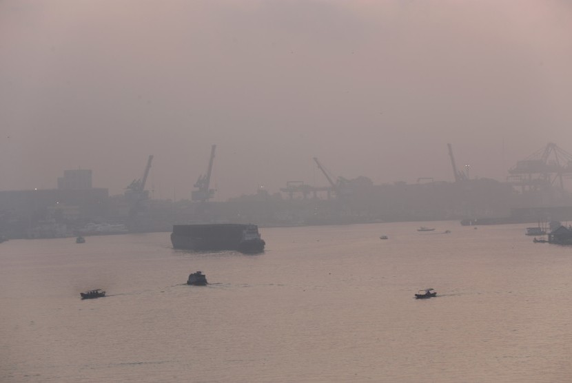 Sejumlah kapal nelayan dan pengangkut batubara melintas di sungai musi yang diselimuti kabut asap, Palembang, Senin (27/7).