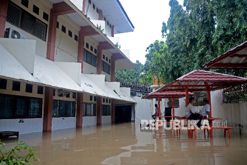  Sejumlah karyawan berjaga saat banjir menggenagi sekolah SMA Negeri 8 , Bukit Duri, Jakarta, Kamis (16/2).