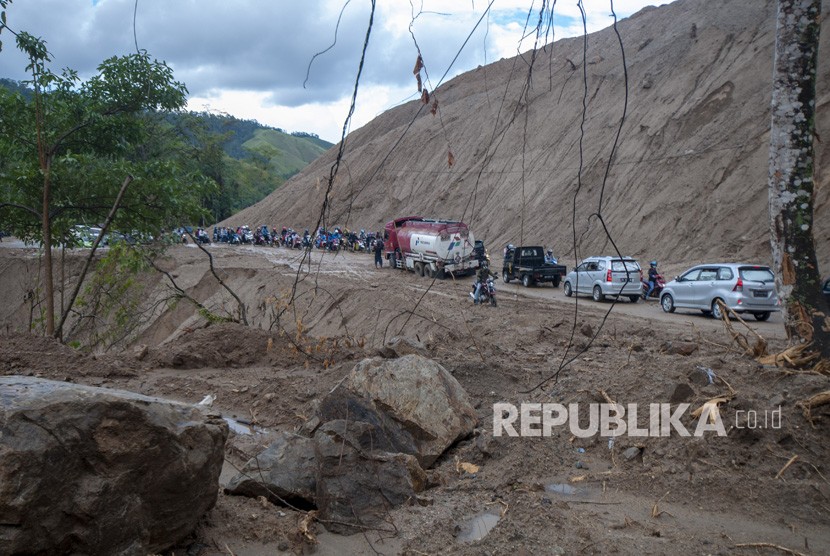 Sejumlah kendaraan berjalan dalam antrean akibat tanah longsor di jalur Trans Sulawesi Km 38, Kabupaten Parigi Moutong, Sulawesi Tengah, Ahad (21/4/2019). 