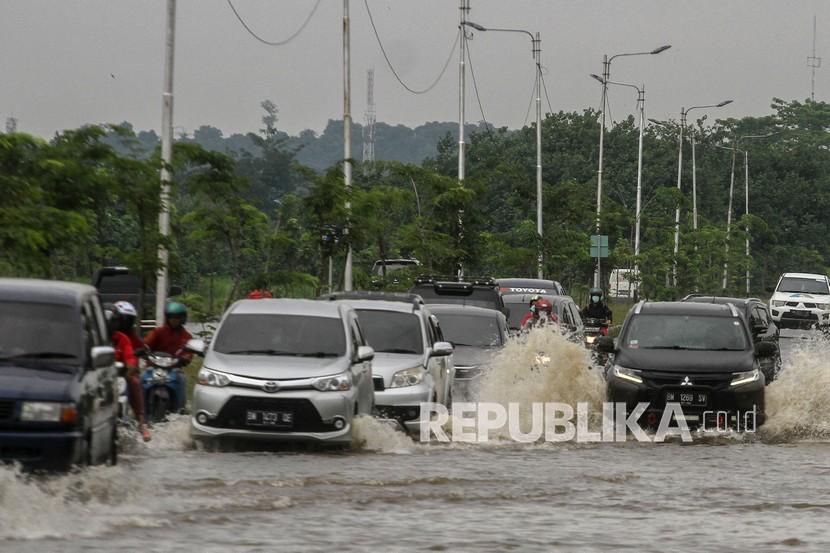 Sejumlah kendaraan bermotor roda empat maupun roda dua melintasi badan jalan yang digenangi banjir akibat hujan deras yang mengguyur Kota Pekanbaru, Riau. 