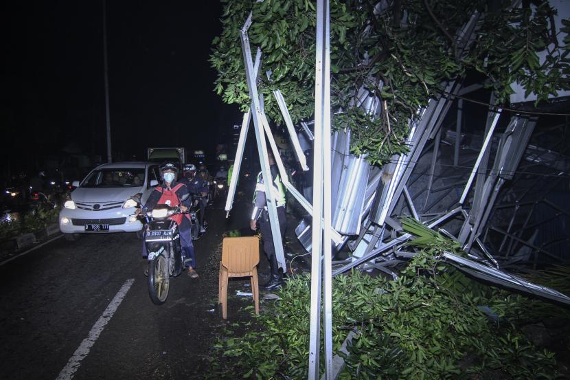 Sejumlah kendaraan melaju di samping atap ruko yang roboh di Jalan Kartini, Depok, Jawa Barat, Selasa (21/9/2021). Hujan deras yang disertai angin kencang mengakibatkan atap ruko roboh dan menghalangi sebagian Jalan Kartini. 