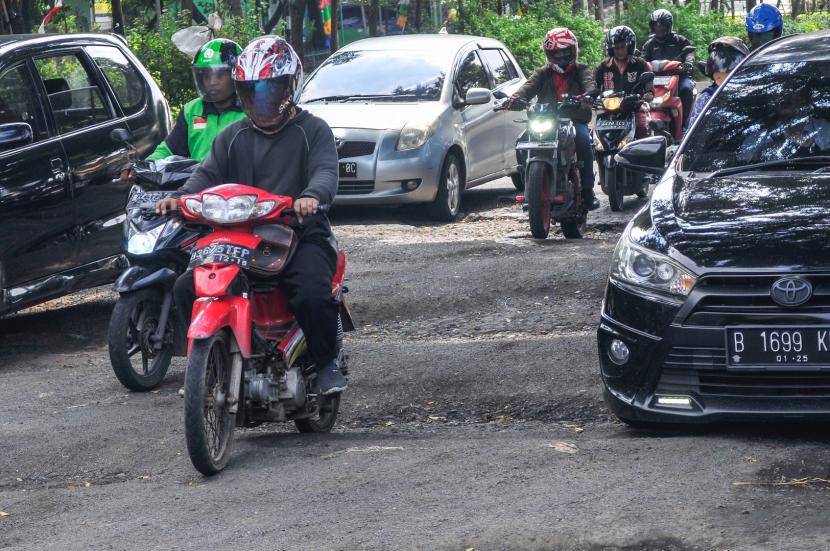 Sejumlah kendaraan melewati jalan rusak di Bekasi. Pj Bupati Dani Ramdan meminta Pusat ikut membantu tangani jalan rusak di Bekasi.
