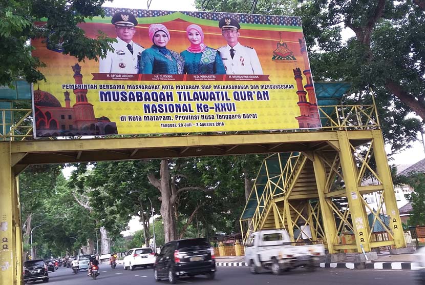 Sejumlah kendaraan melintas di bawah billboard MTQ Nasional XXVI di Kota Mataram, Nusa Tenggara Barat, Kamis (21/7/2016).