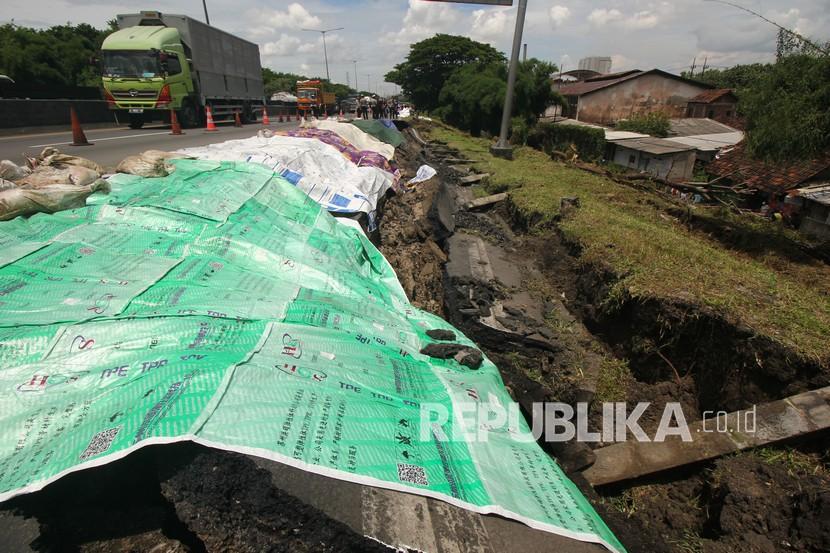 Sejumlah kendaraan melintas di dekat jalan tol yang ambles di ruas tol Surabaya-Gempol KM 06+200, di Surabaya, Jawa Timur, Rabu (27/1/2021). Jalan tol ambles yang terjadi pada Selasa (26/1) yang sebelumnya ditemukan retakan pada Senin (25/1) di lokasi tersebut mengakibatkan kemacetan lalu lintas yang sangat panjang.