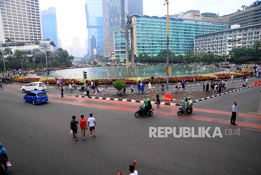  Sejumlah kendaraan melintas diantara warga yang berolah raga di Bunderan Hotel Indonesia, Jakarta, Ahad (10/7).  (Republika/Agung Supriyanto)