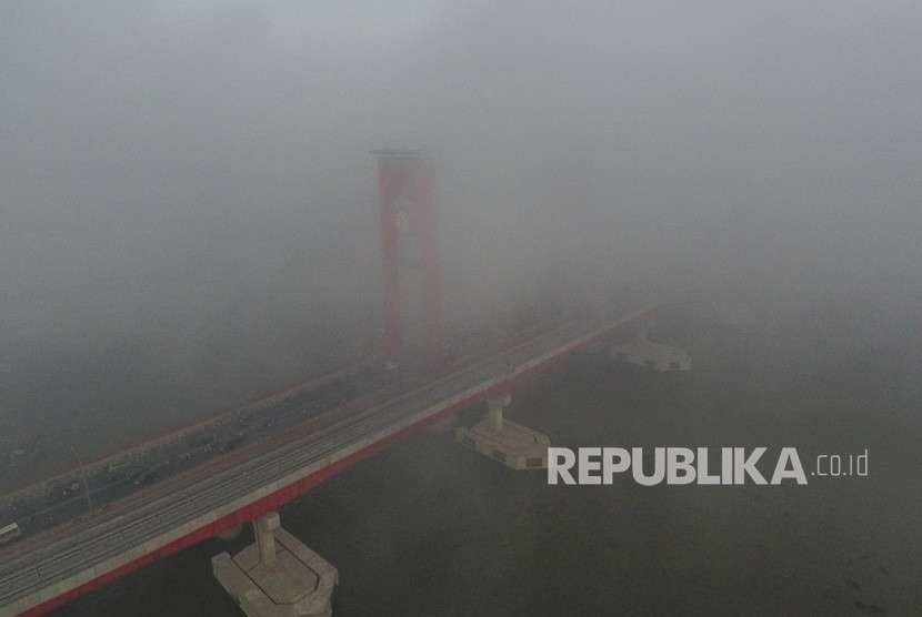 Sejumlah kendaraan melintas diatas jembatan ampera yang tertutup kabut asap di Palembang, Sumatera Selatan, Jumat (5/10). 