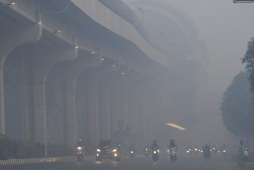 Sejumlah kendaraan melintas Jalan Gubernur Ahmad Bastari Palembang yang diselimuti kabut asap di Palembang, Sumatera Selatan. 