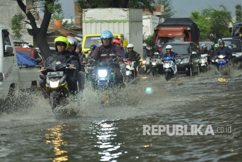 Sejumlah kendaraan melintasi luapan air yang menggenangi jalan di kawasan industri Kahatex, Kecamatan Cimanggung, Kabupaten Sumedang, Selasa (28/3). Banjir di kawasan tersebut itu kerap terjadi meskipun dengan intensitas hujan yang relatif kecil 