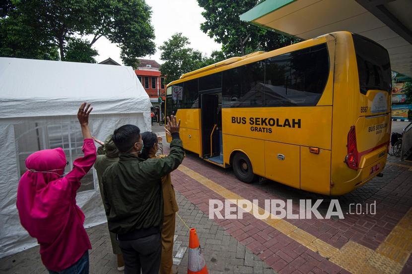 Sejumlah kerabat melambaikan tangan ke arah bus pembawa pasien COVID-19 ke Rumah Sakit Darurat Penanganan COVID-19 Wisma Atlet Kemayoran dari Puskesmas Duren Sawit, Jakarta.