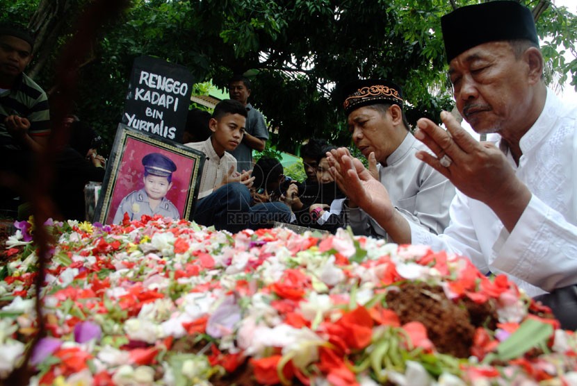   Sejumlah kerabat tengah memanjatkan doa saat pemakaman almarhum Renggo Kadapi di TPU Kampung Asem, Halim, Jakarta Timur, Ahad (4/5).  (Republika/Yasin Habibi)