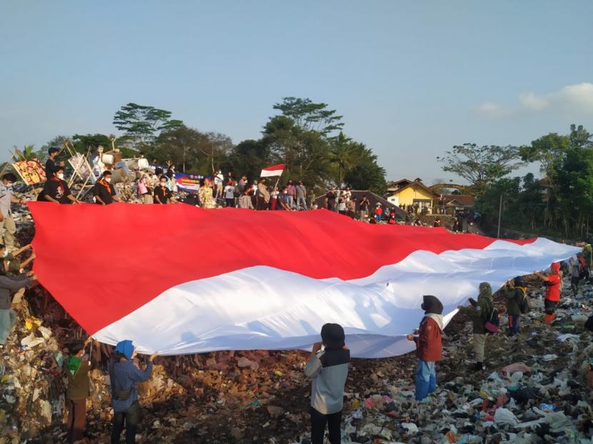 Sejumlah komunitas di Kota Tasikmalaya melakukan aksi pengibaran bendera merah-putih berukuran raksasa di TPA Ciangir, Kota Tasikmalaya, Ahad (15/8). Aksi itu dilakukan untuk menyambut hari kemerdekaan ke-76 Indonesia. 