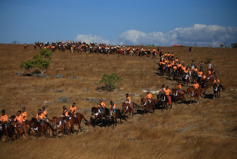 Sejumlah lelaki Sumba menunggangi kuda berbalut sarung tenun ikat Sumba dalam acara Parade Kuda dari Savana Walakiri menuju Pantai Walakiri pada Festival 1001 Kuda Sandelwood di Sumba Timur, NTT, Kamis (12/7).