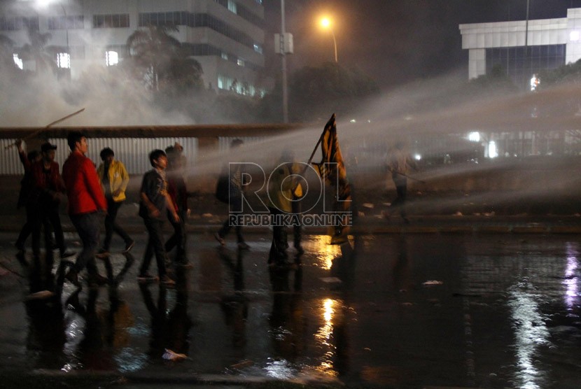    Sejumlah mahasiswa menahan semprotan air dari water cannon saat demo tolak BBM di depan Komplek Parlemen, Jakarta, Senin (17/6) malam.   (Republika/Yasin Habibi)