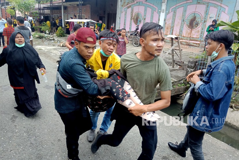 Sejumlah mahasiswa menggotong rekannya yang pingsan akibat terkena gas air mata di depan Kantor DPRK Aceh Barat, Aceh, Kamis (26/9/2019).