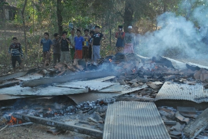 Sejumlah massa menyaksikan puing pemukiman warga Syiah yang dibakar, di Desa Karanggayam, Omben, Sampang, Jawa Timur, Ahad (26/8).