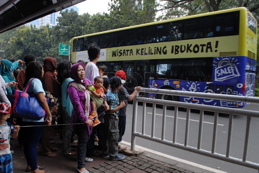 Sejumlah masyarakat mengantre untuk naik Bus Tingkat Pariwisata di Jalan Medan Merdeka Barat, Jakarta Pusat, Jumat (18/4). (Republika/Rakhmawaty La'lang)
