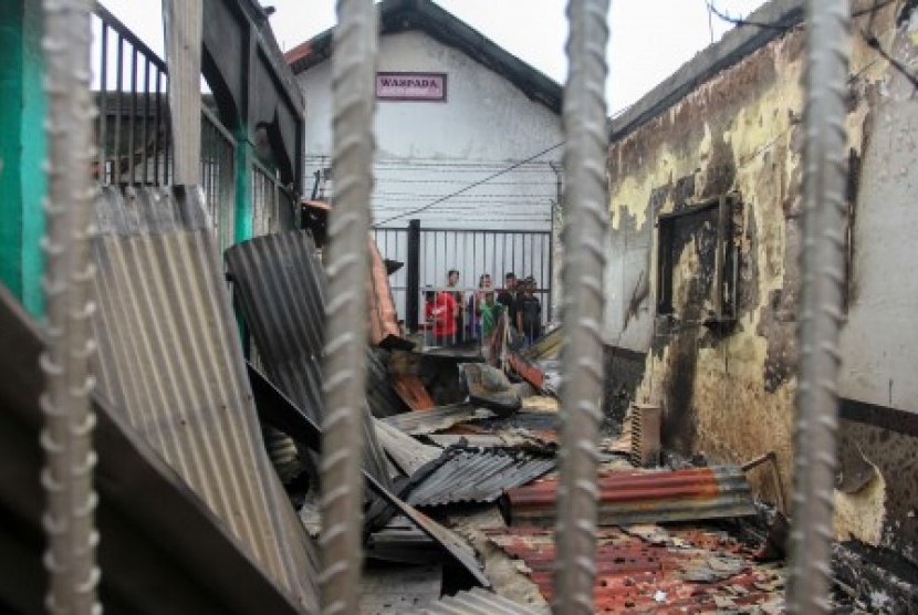Sejumlah narapidana berada di dekat puing bangunan Rutan yang hangus terbakar pasca kerusuhan di Rutan Kelas II B Siak Sri Indrapura, Kabupaten Siak, Riau, Sabtu (11/5/2019). 
