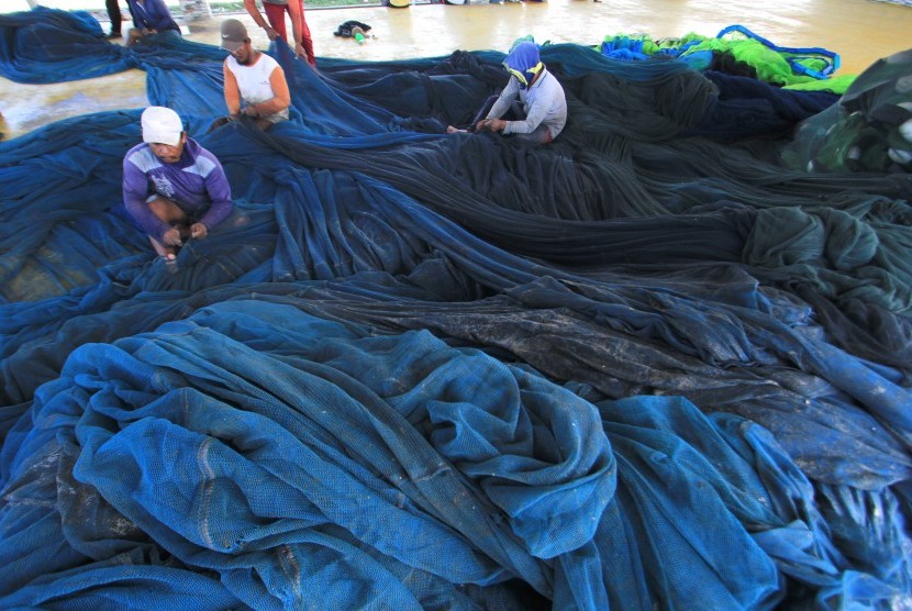 Sejumlah nelayan memperbaiki jaring pukat kursin di pelabuhan Dadap, Juntinyuat, Indramayu, Jawa Barat, disela tak melaut akibat musim baratan.