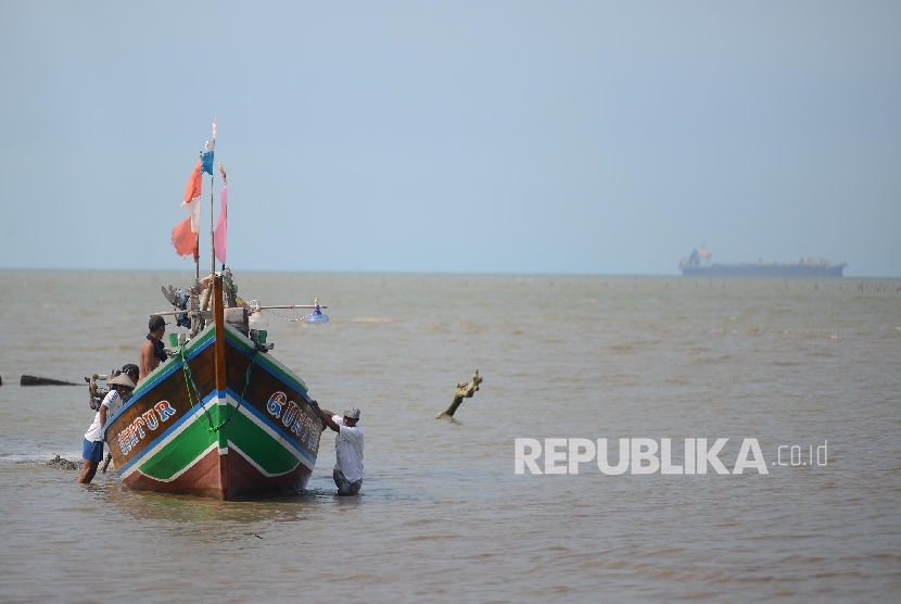 Sejumlah nelayan terpaksa mendorong perahu akibat dangkalnya air laut di perairan Serang, Banten, Rabu (27/4).Republika/Raisan Al Farisi