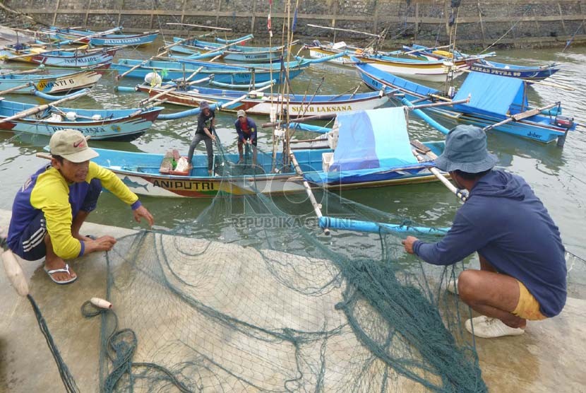   Sejumlah nelayan yang tidak dapat melaut akibat cuaca buruk, memperbaiki jaring di Pantai Jayanti, Kecamatan Cidaun, Kabupaten Cianjur, Senin (13/1).   (Republika/Edi Yusuf)