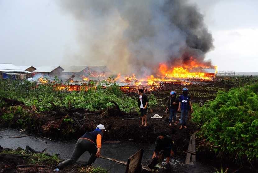 Sejumlah orang berlari meninggalkan lokasi permukiman warga eks-Gafatar yang dibakar massa di kawasan Monton Panjang, Dusun Pangsuma, Desa Antibar, Mempawah Timur, Kabupaten Mempawah, Kalbar, Selasa (19/1). (Antara/Jessica Helena Wuysang)