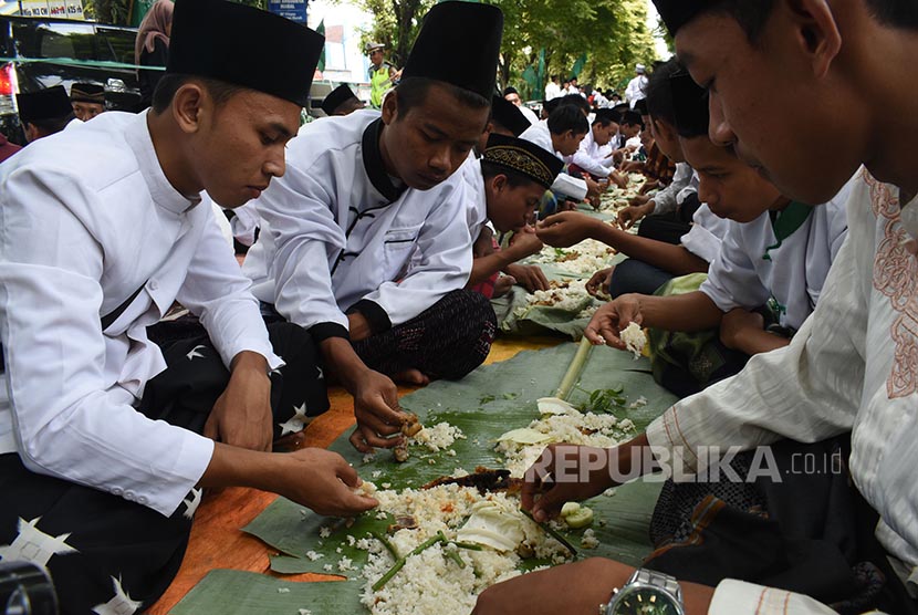Sejumlah orang makan bersama ala pesanten saat peringatan Hari Santri 2016 di Magetan, Jawa Timur, Sabtu (22/10). Ribuan santri mengikuti istighatsah dan apel dilanjutkan makan bersama beralaskan daun pisang untuk memperingati hari santri.