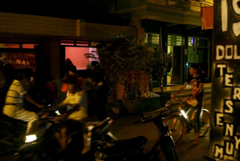 Sejumlah orang melintas tak jauh dari salah satu wisma kawasan Lokalisasi Dolly, Surabaya, Kamis (19/6) malam. Meski Pemerintah Kota Surabaya telah menggelar Deklarasi Surabaya Bebas Prostitusi namun sejumlah wisma dan tempat hiburan malam di kawasan Lokal