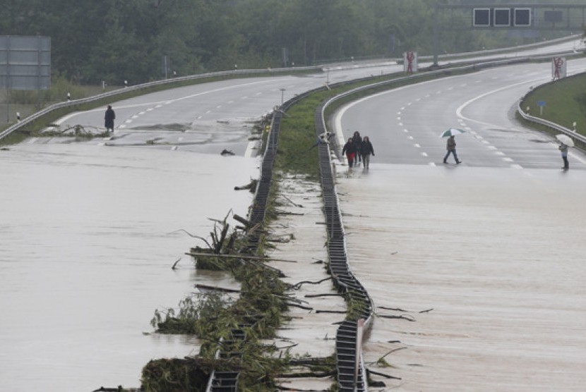   Sejumlah orang melintasi jalan bebas hambatan yang terpotong arus banjir di Grabenstaett dekat Traunstein, Jerman, Senin (3/6) waktu setempat.    (AP/Matthias Schrader)