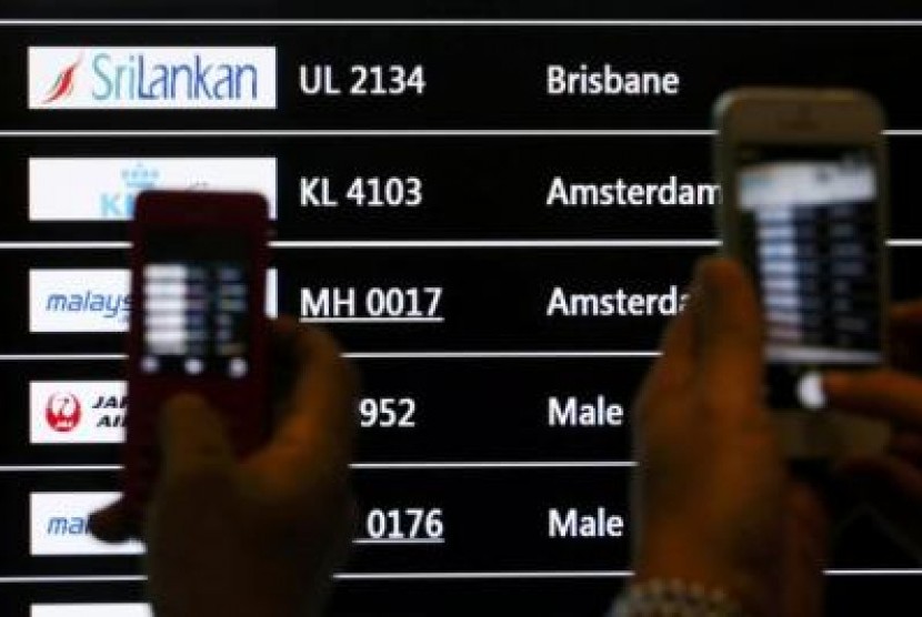 Sejumlah orang memotret layar yang menunjukkan kedatangan pesawat Maskapai Malaysia Airlines MH-17 di Bandara Internasional Kuala lumpur, Jumat (18/7).