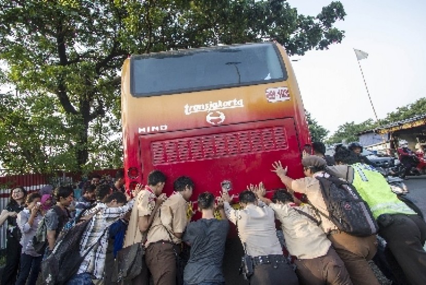   Sejumlah orang mendorong Bus Transjakarta yang mogok di kawasan Manggarai, Jakarta, Jumat (13/3).